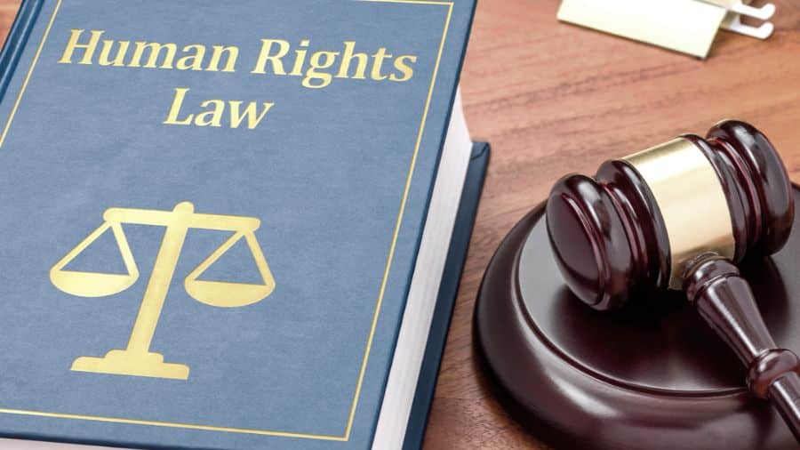 A judge's gavel placed beside an open book titled "Human Rights Law.